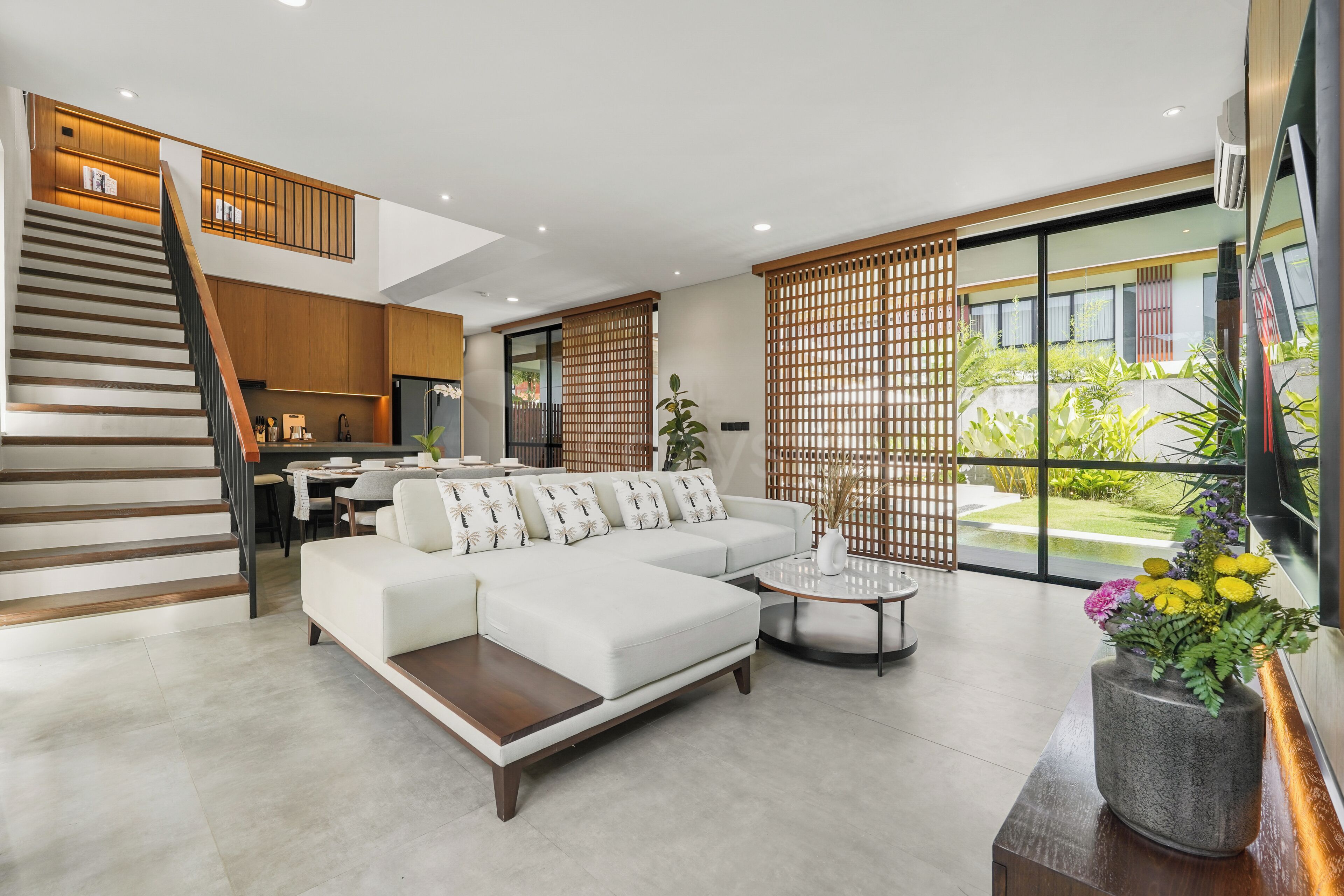 A modern living room with a sofa, coffee table, and a staircase leading to a dining area.