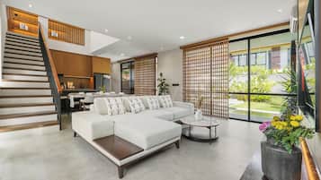 A modern living room with a sofa, coffee table, and a staircase leading to a dining area.