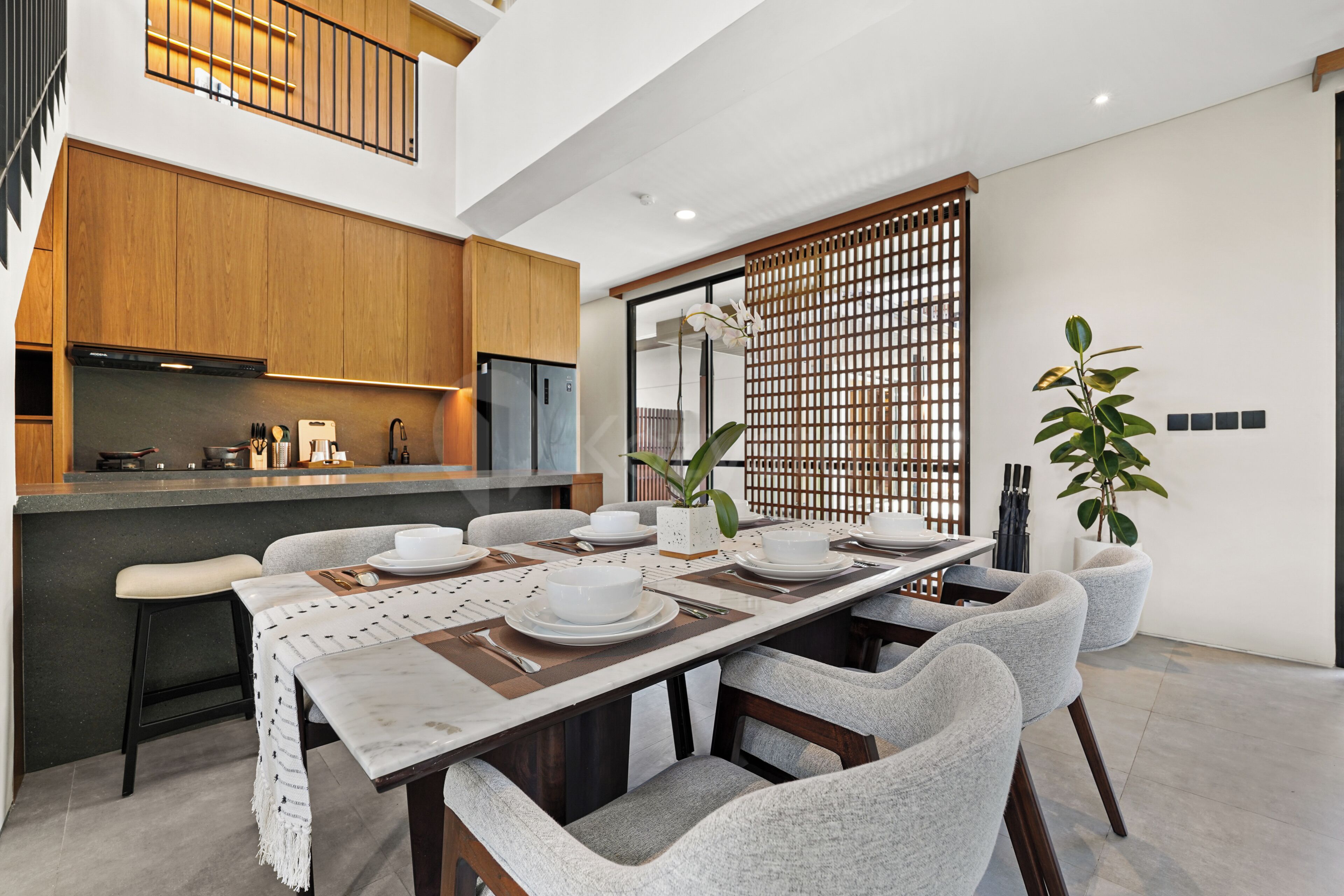 A modern kitchen with wooden cabinets, a built-in oven, and a dining area with a long table set for four.