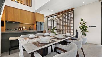 A modern kitchen with wooden cabinets, a built-in oven, and a dining area with a long table set for four.