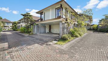 A modern two-story house with a covered entrance and a paved driveway.