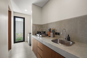 A modern kitchen with a stainless steel sink, a gas stove, and wooden cabinets.
