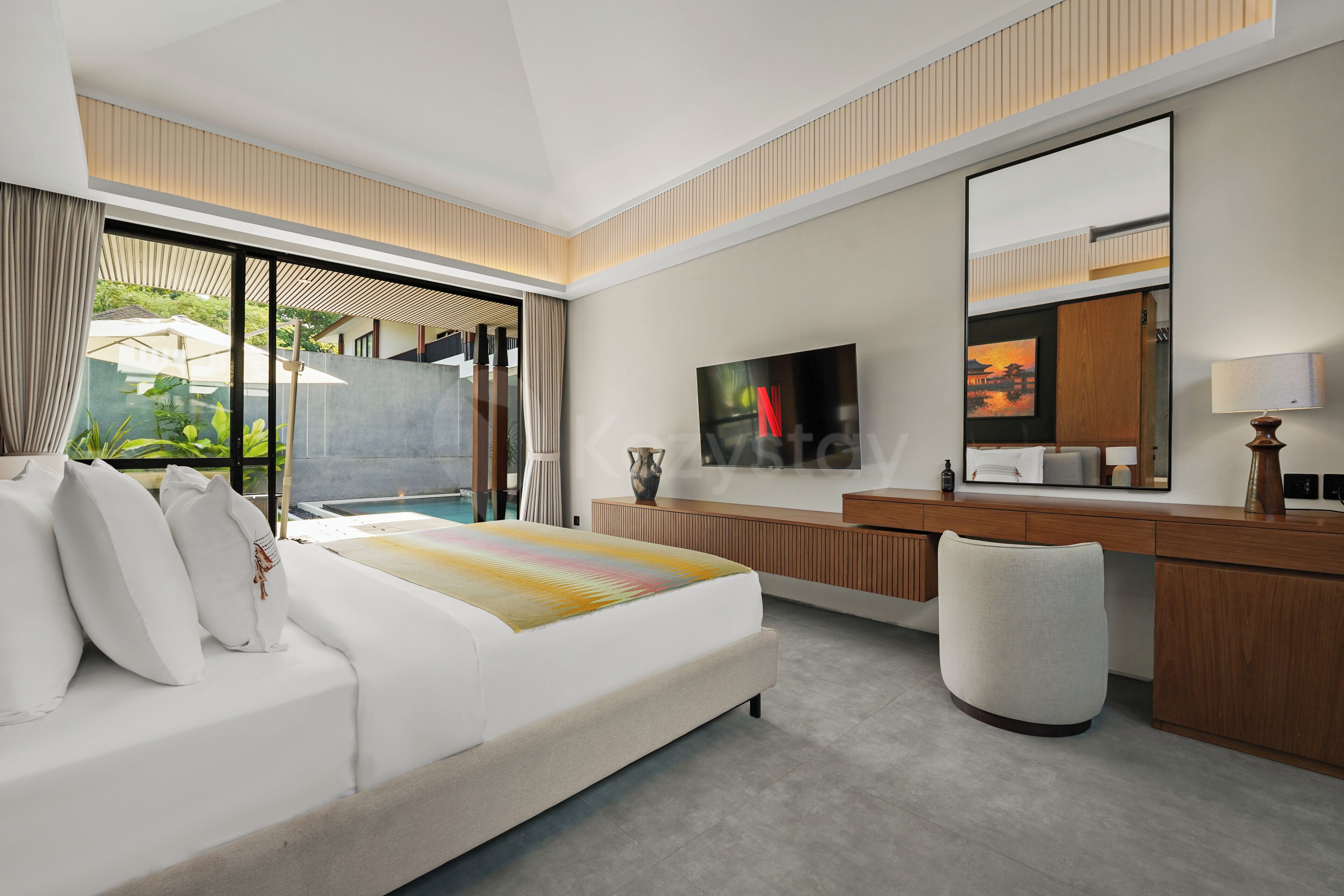 A modern hotel room with a large bed, a desk, a television, and a view of the outdoors.