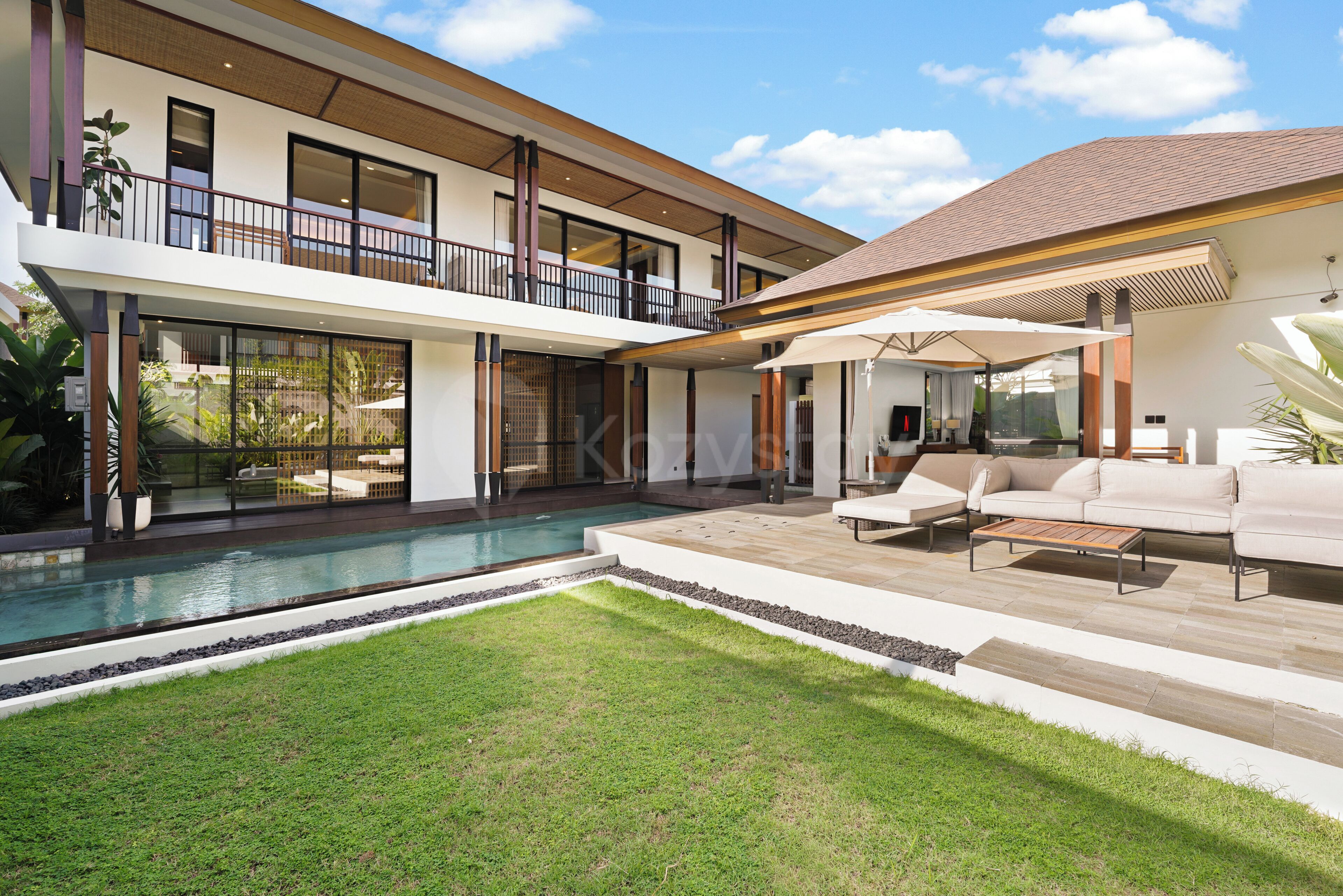 A modern two-story house with a swimming pool, outdoor seating, and a large balcony.