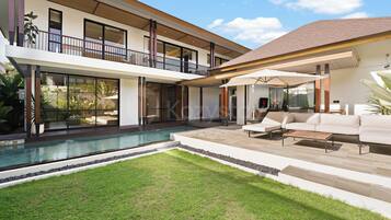 A modern two-story house with a swimming pool, outdoor seating, and a large balcony.