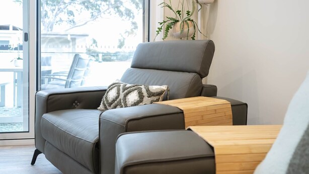 Uma sala de estar moderna com um sofá de couro, uma mesa de centro de madeira e uma planta em vaso.