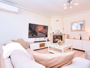 A modern living room with a flat-screen TV, a fireplace, and a sofa. - LOS PINOS - VILLA 7 by Interhome (El Carmoli)