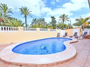 A swimming pool with a curved edge, surrounded by a white fence and palm trees. - LOS PINOS - VILLA 7 by Interhome (El Carmoli)