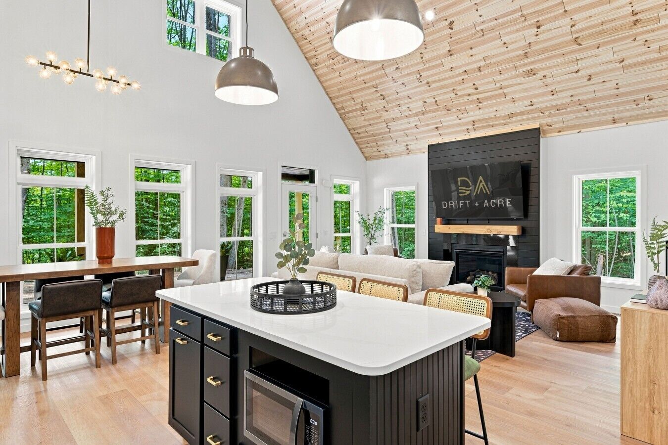 A spacious kitchen with a central island, a dining area with chairs, a seating area with sofas, and a fireplace.