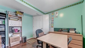 A room with a wooden table, chairs, a bookshelf, a filing cabinet, and a bulletin board with educational materials. - Shalom Casablanca Home (Edmonton)