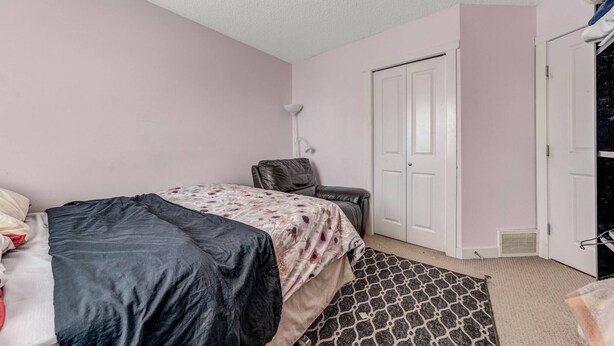 A bedroom with a bed, a chair, a wardrobe, and a door. - Shalom Casablanca Home (Edmonton)