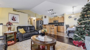 A living room with a black leather sofa, a coffee table, and a dining area with a Christmas tree. - Shalom Casablanca Home (Edmonton)