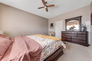 A bedroom with a bed, dresser, ceiling fan, and a door. - Shalom Casablanca Home (Edmonton)
