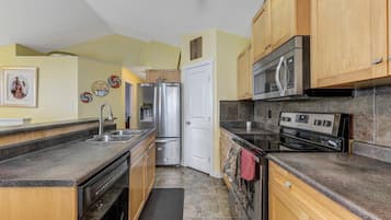 Una cucina con mobili in legno, elettrodomestici in acciaio inossidabile e zoccolo a mosaico.