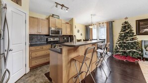 A kitchen with wooden cabinets, a built-in oven, and a bar area with stools. - Shalom Casablanca Home (Edmonton)