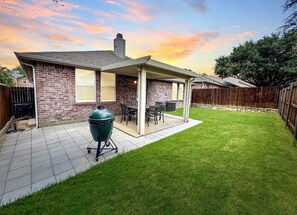A backyard with a patio, a barbecue grill, and a covered seating area. - Stylish 4-bedroom retreat with 3 king beds and twin trundle in charming Frisco. (Frisco)