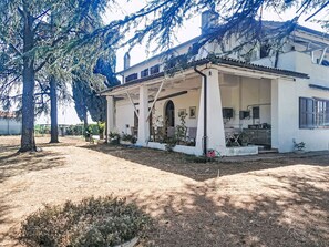 Een wit gebouw met een overdekte patio, een garage en een kleine tuin.