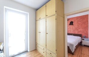 Ein Zimmer mit einem großen Kleiderschrank, einem Bett mit weißer Bettdecke und einer roten Wand.