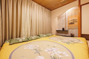 Ein Schlafzimmer mit einem Bett, Vorhängen, einem Nachttisch und einem Wandregal.