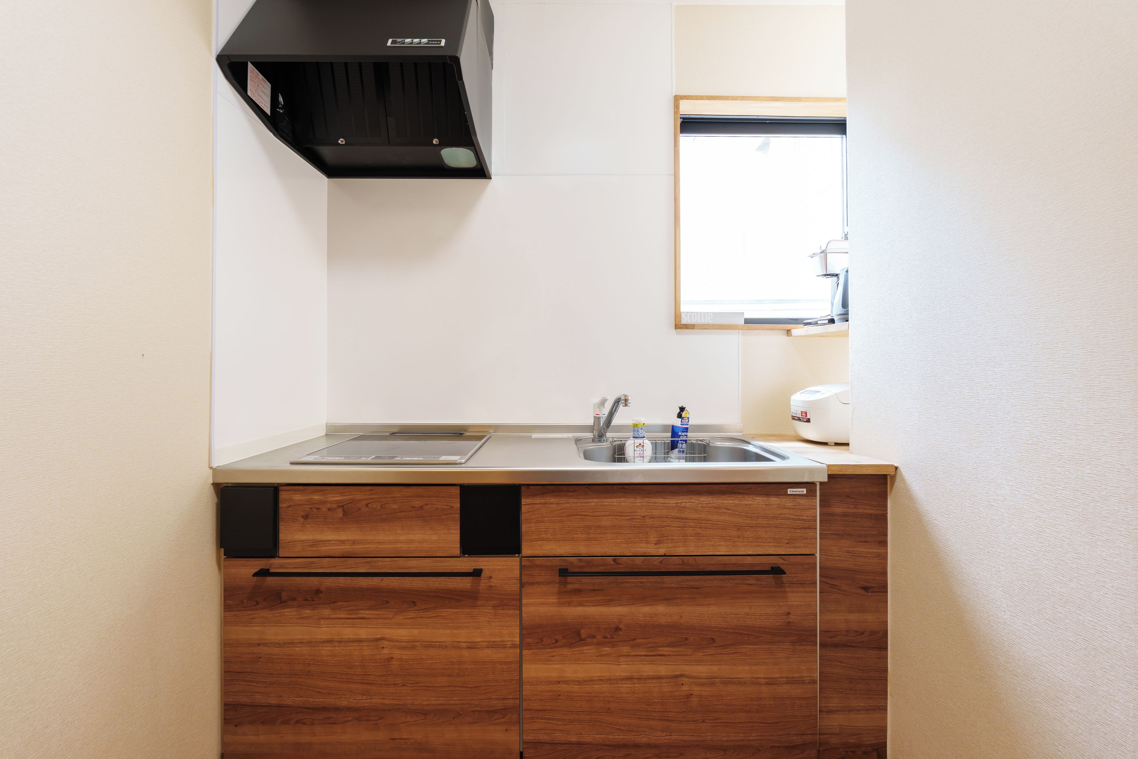 A compact kitchen with a sink, a stove, and wooden cabinets.