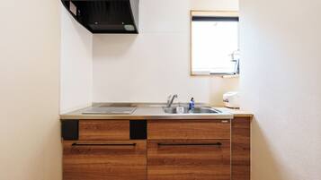 A compact kitchen with a sink, a stove, and wooden cabinets.