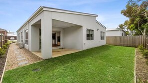 Une maison moderne de plain-pied dotée d’un patio couvert, d’une pelouse bien entretenue et d’une clôture en bois.