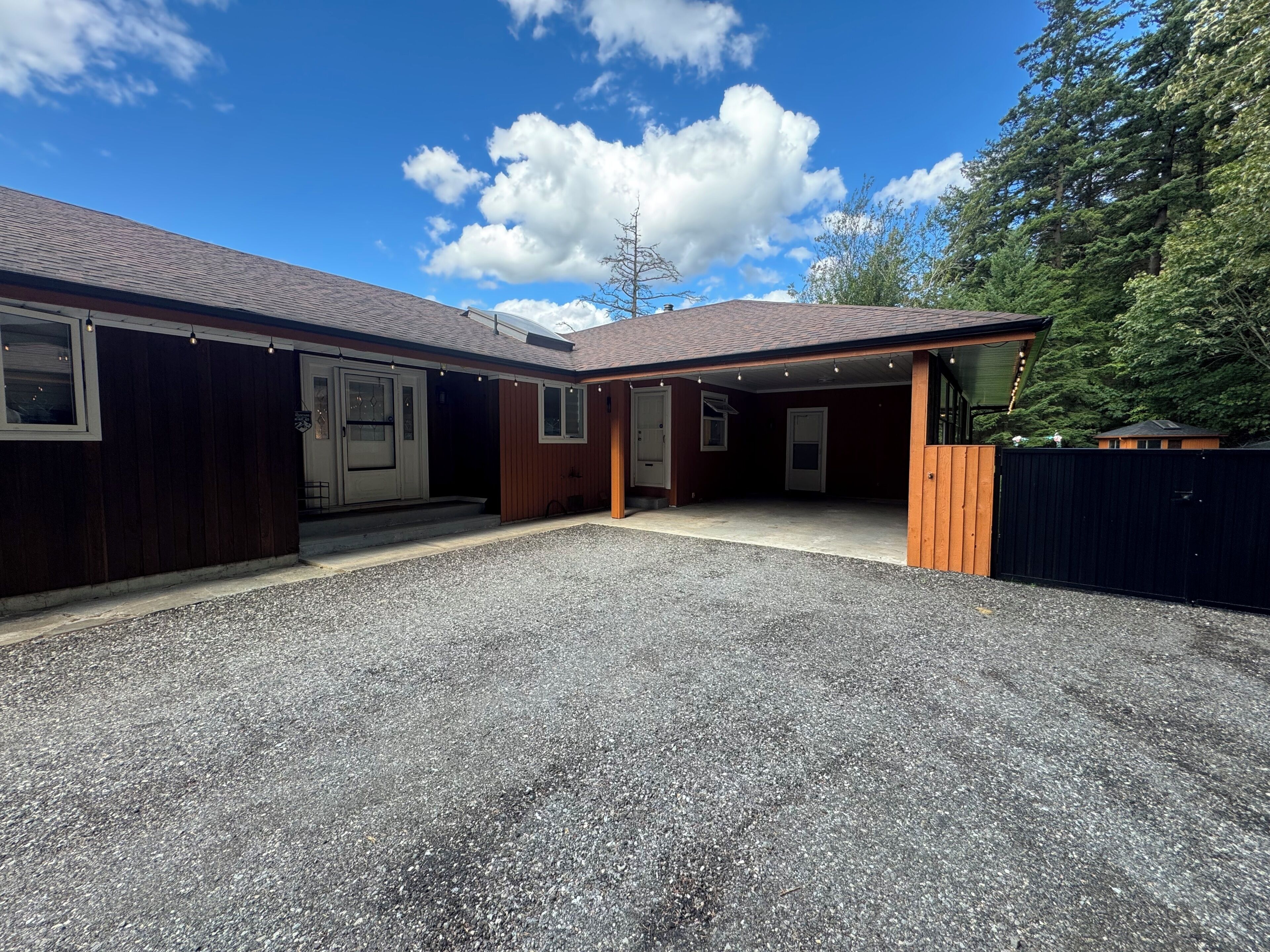 A two-story building with a covered patio area and a gravel driveway.