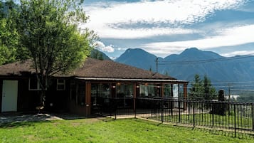 A small building with a porch, surrounded by a fenced area and a grassy lawn.
