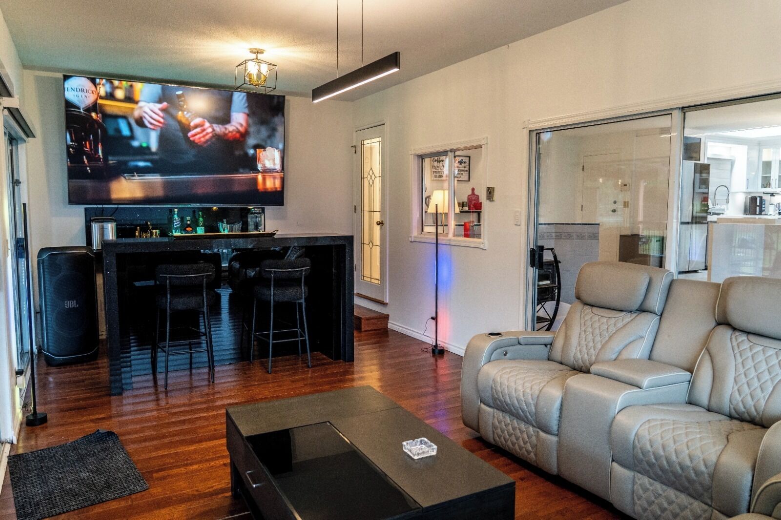 A modern living room with a bar area, a sofa, and a television.