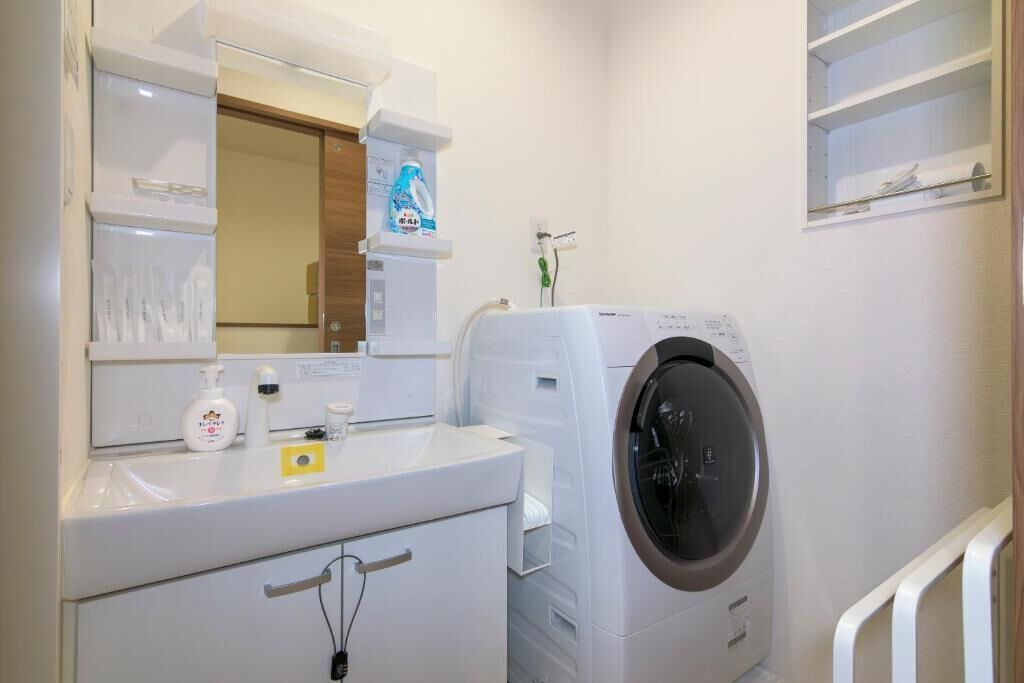 Un espacio para lavar ropa con lavadora, lavabo y espejo.