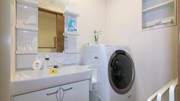 Un espacio para lavar ropa con lavadora, lavabo y espejo.
