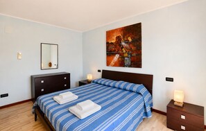 A hotel room with a bed, a dresser, a nightstand, a bedside lamp, a wall-mounted mirror, and a painting. - Gorgeous apartment in Saline Joniche with WiFi (Saline Joniche)