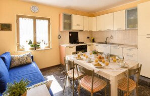 A compact kitchen with a dining table set for breakfast, a sofa, and a window with curtains. - Gorgeous apartment in Saline Joniche with WiFi (Saline Joniche)