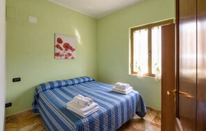 Ein Zimmer mit einem Bett, einem Vorhangfenster, einem Bild an der Wand und einer Tür.