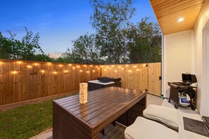 An outdoor patio with a wooden table, a hot tub, and a grill. - Spacious 4-bedroom house in Houston Texas Hot tub/ Play room. (Houston)