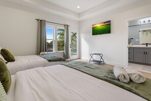 Ein Schlafzimmer mit zwei Betten, Blick ins Freie, einem Gemälde und einem Badezimmer mit Spiegel.