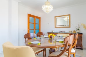 A dining room with a round table, chairs, a chandelier, a mirror, and a door. - SON JANER - Beautiful apartment for 6 people in Can Picafort. Free WiFi (Muro)