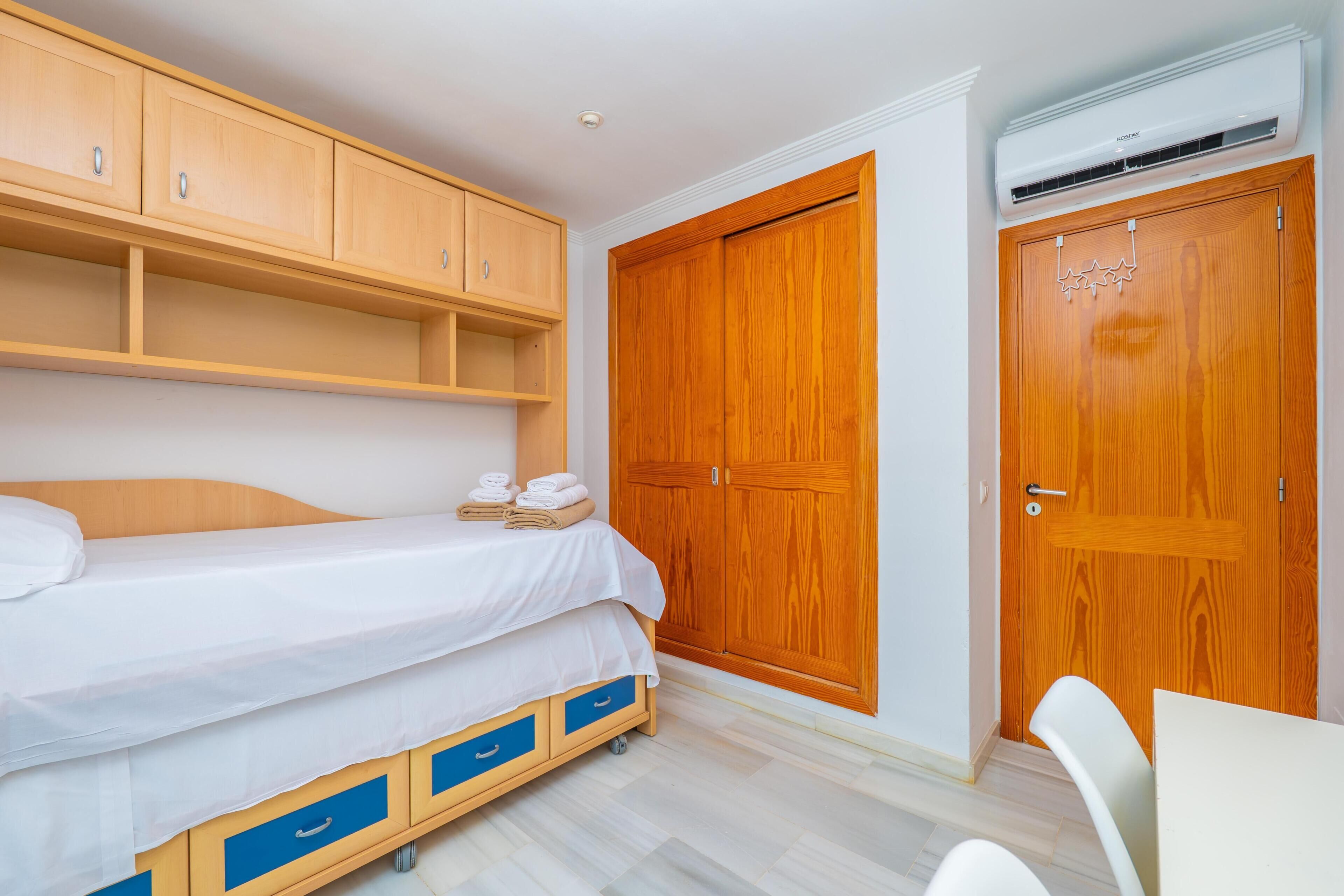 Un dormitorio con cama, armario de madera y escritorio con silla.