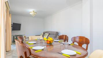 Un comedor con una mesa redonda, sillas y una araña.
