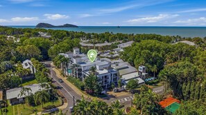 Un barrio residencial con una casa grande rodeada de abundante vegetación y vista al mar.
