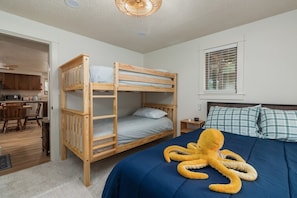 Ein Etagenbett mit blauer Matratze und einem weichen, plüschigen Oktopus-Spielzeug darauf.