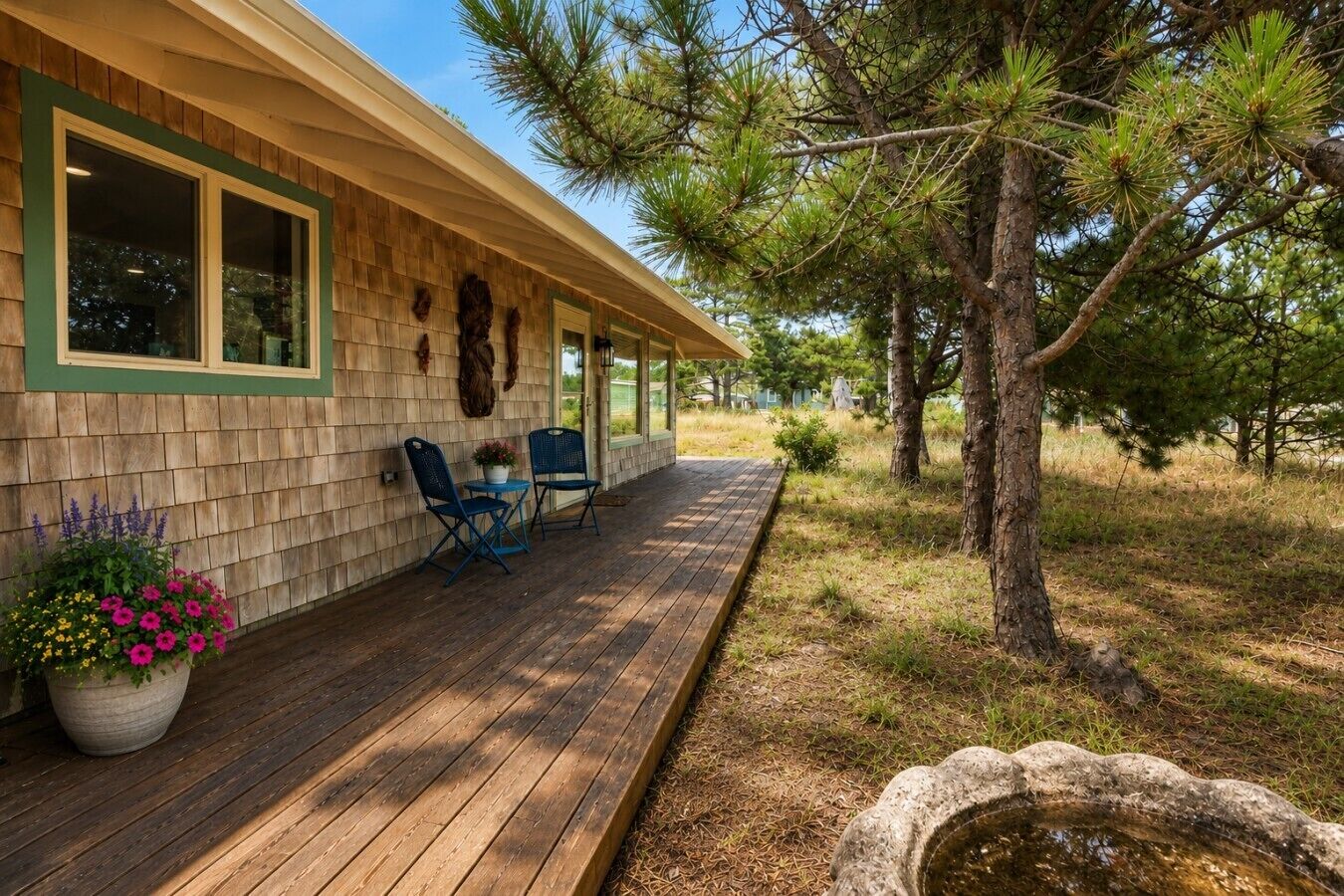A wooden deck with outdoor seating, a stone planter, and a pine tree.