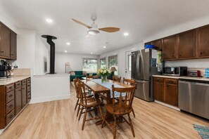 Eine moderne Küche mit Holzschränken, einem Edelstahlkühlschrank und einem Essbereich mit Holztisch und Stühlen.