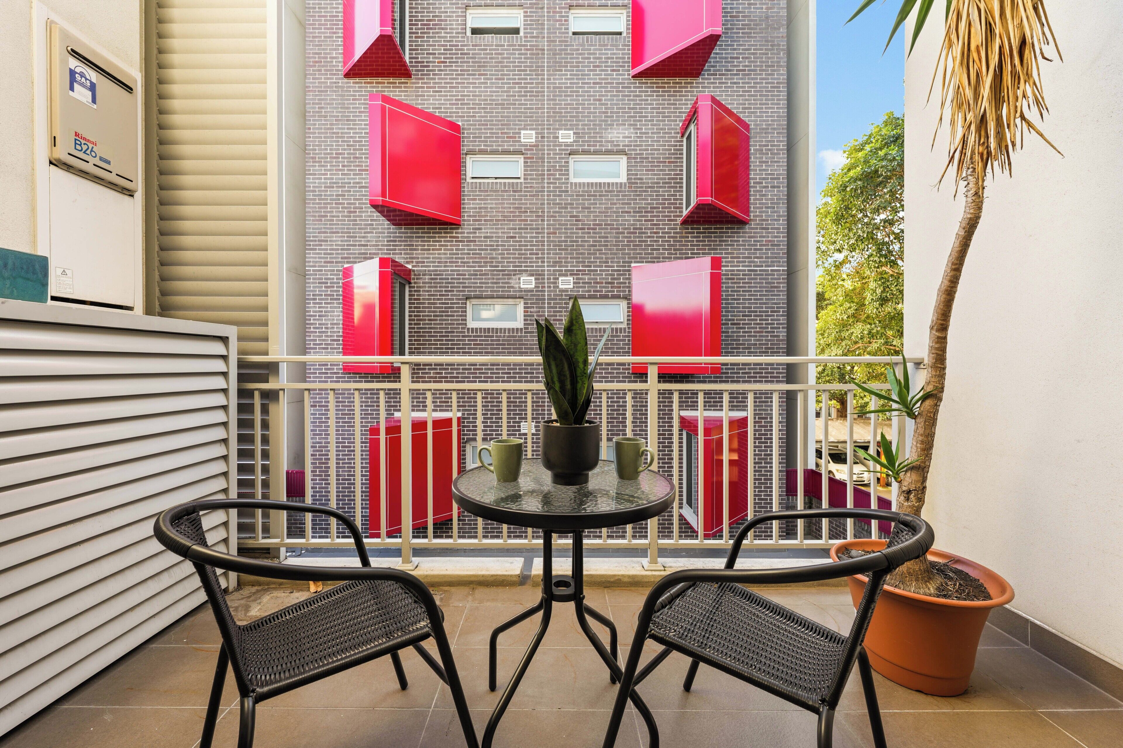 A balcony with two chairs, a table, and a potted plant.