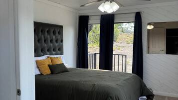 A bedroom with a bed, a ceiling fan, and a view through the window.
