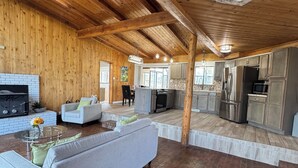 A spacious living area with a fireplace, a sofa, and a kitchen in the background.