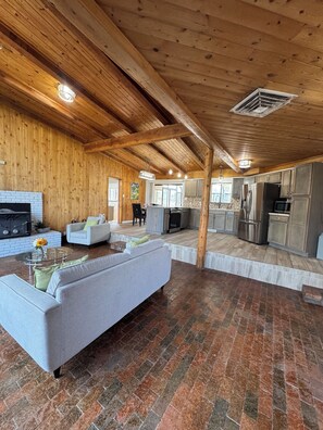 A spacious living area with a fireplace, a sofa, and a kitchen in the background.