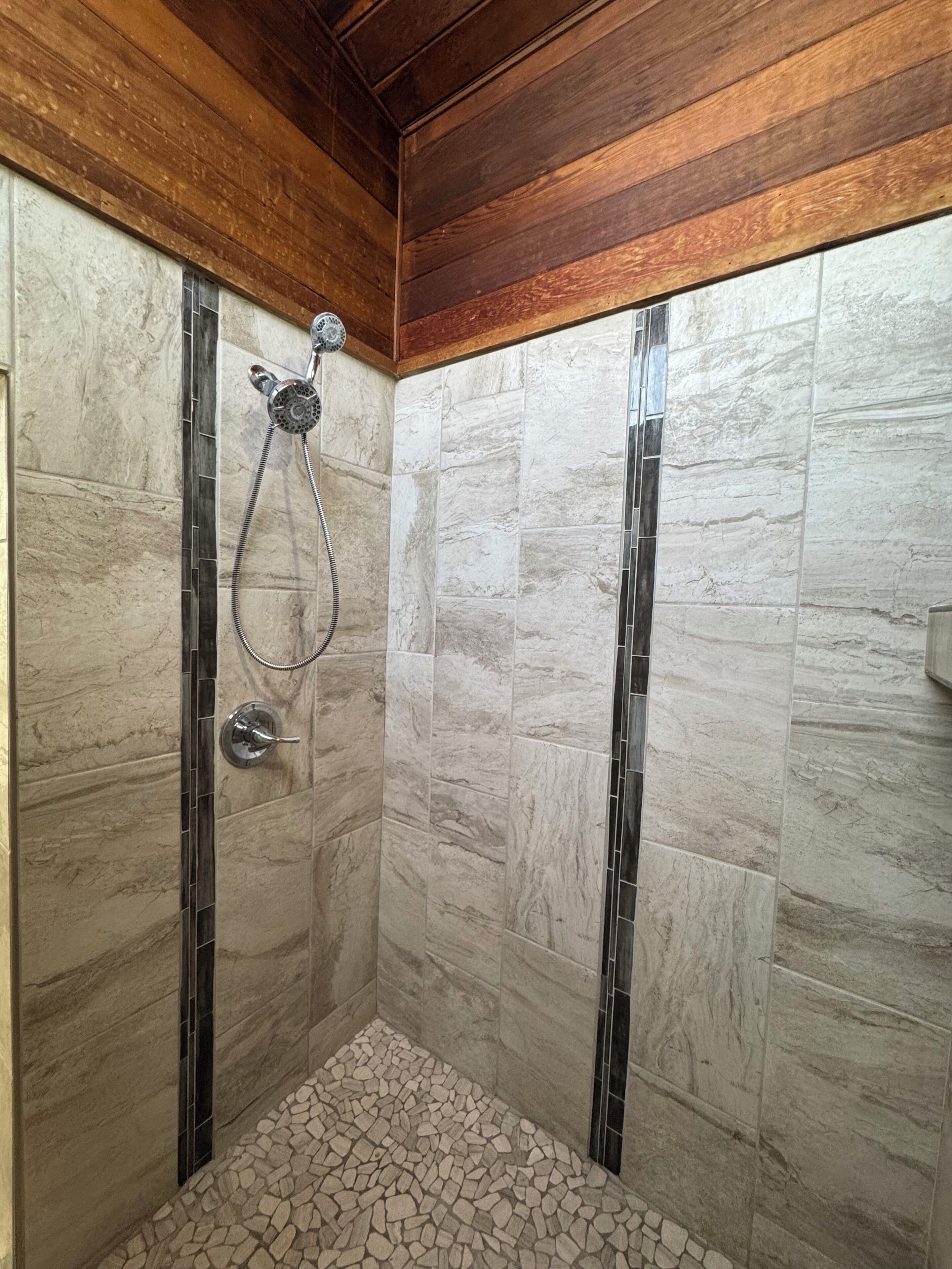 A shower with a tiled floor and a wooden ceiling.