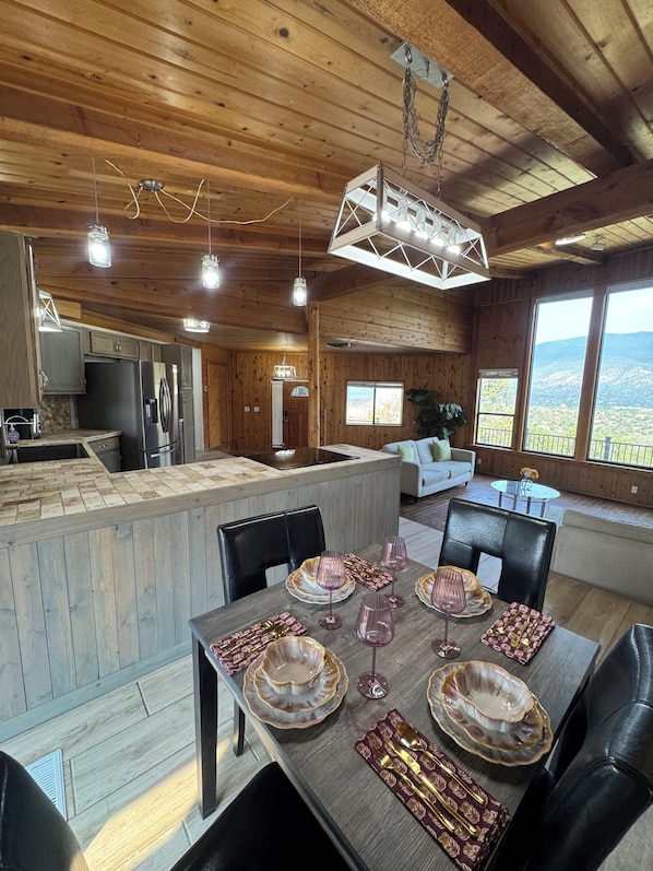 Un interior de madera con comedor, cocina y ventanas amplias que ofrecen una vista.