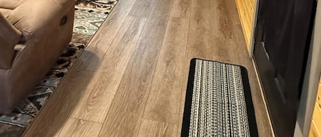 Un interior de madera con televisor, sofá y cama con cortina negra.